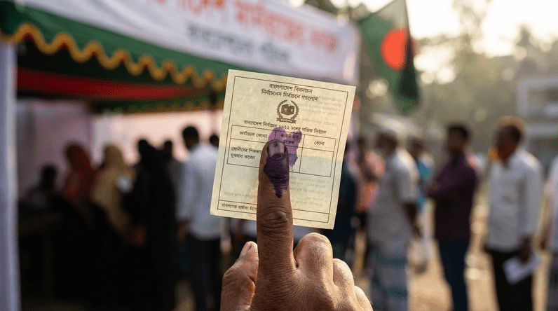 Hand holding Bangladesh voting ballot paper with ink-stained finger at polling station during 2026 historic election